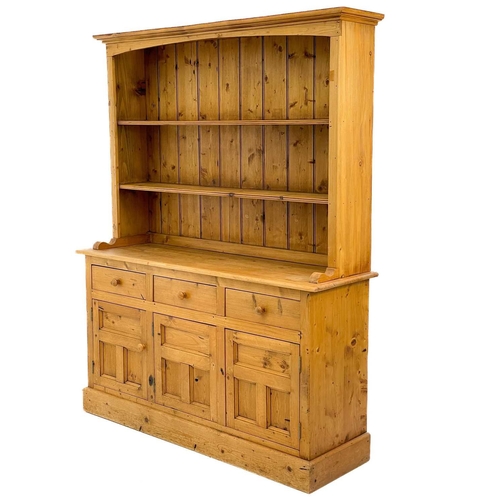 675 - A 20th century pine dresser. The dresser rack on three short drawers and three panelled doors on a p... 