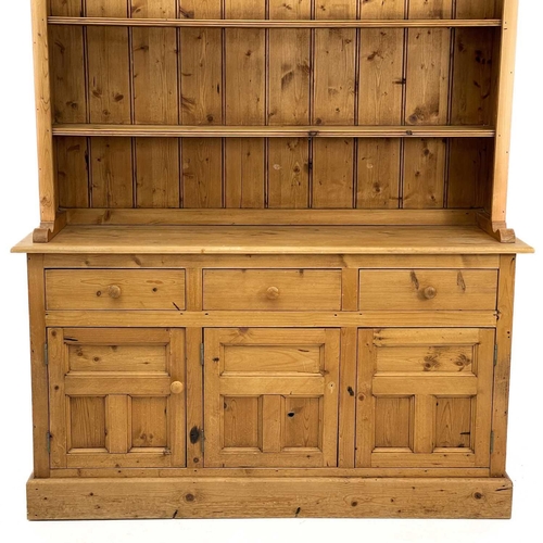 675 - A 20th century pine dresser. The dresser rack on three short drawers and three panelled doors on a p... 