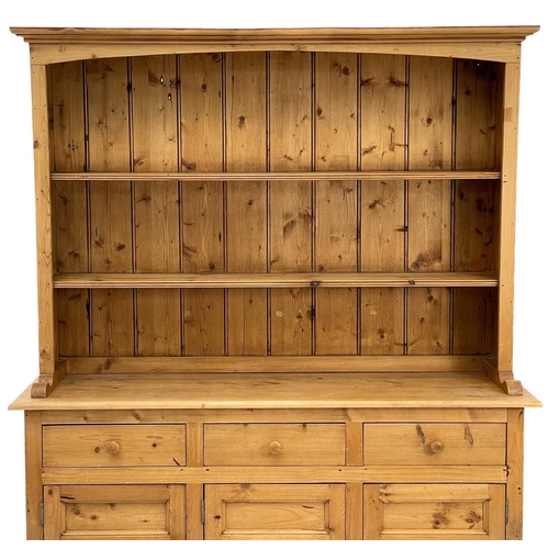 675 - A 20th century pine dresser. The dresser rack on three short drawers and three panelled doors on a p... 