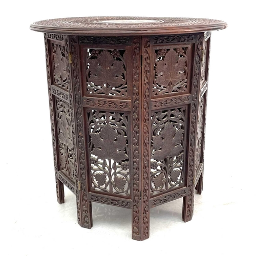 717 - An Anglo-Indian brass inlaid teak occasional table. With carved decoration, circular top and folding... 