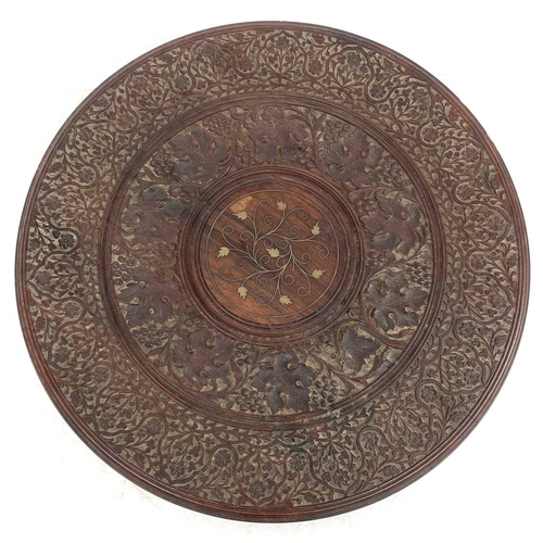 717 - An Anglo-Indian brass inlaid teak occasional table. With carved decoration, circular top and folding... 