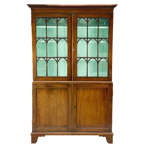 747 - A 19th century mahogany bookcase cabinet. With a dentil cornice above arched glazed doors, the lower... 