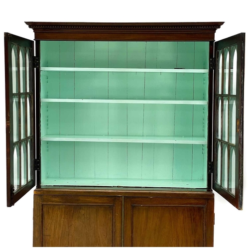 747 - A 19th century mahogany bookcase cabinet. With a dentil cornice above arched glazed doors, the lower... 