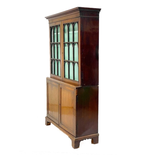 747 - A 19th century mahogany bookcase cabinet. With a dentil cornice above arched glazed doors, the lower... 