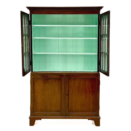 747 - A 19th century mahogany bookcase cabinet. With a dentil cornice above arched glazed doors, the lower... 