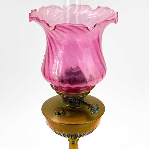 90 - A Victorian brass oil lamp. With cranberry glass swirl shade, height 58cm.