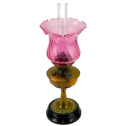 90 - A Victorian brass oil lamp. With cranberry glass swirl shade, height 58cm.