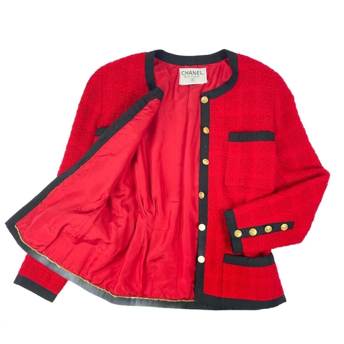 581 - A Chanel 1980's red boucle jacket with gold plated buttons and black trim. Label cut, size S approxi... 