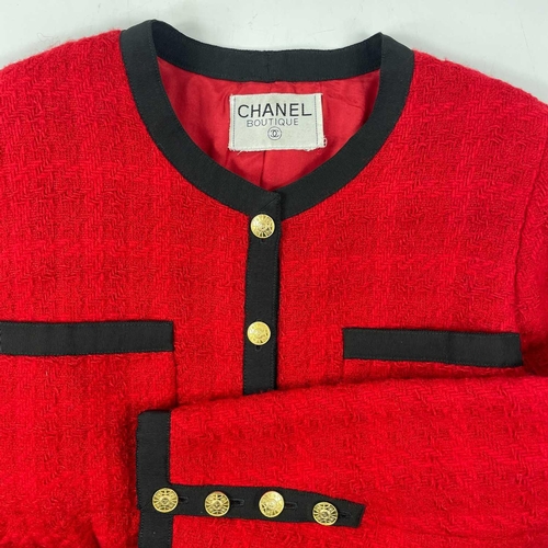 581 - A Chanel 1980's red boucle jacket with gold plated buttons and black trim. Label cut, size S approxi... 