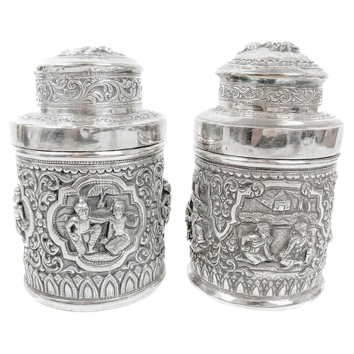 1017 - Two Burmese silver lidded cannisters, mid 20th century Repousse decorated witrh figures in landscape... 