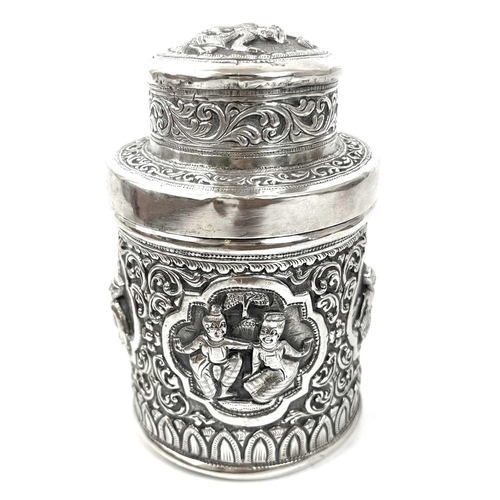 1017 - Two Burmese silver lidded cannisters, mid 20th century Repousse decorated witrh figures in landscape... 