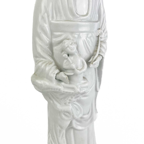 1112 - A Chinese blanc de chine figure of Guanyin, 18th/19th century. Stood holding a child in her arms, he... 