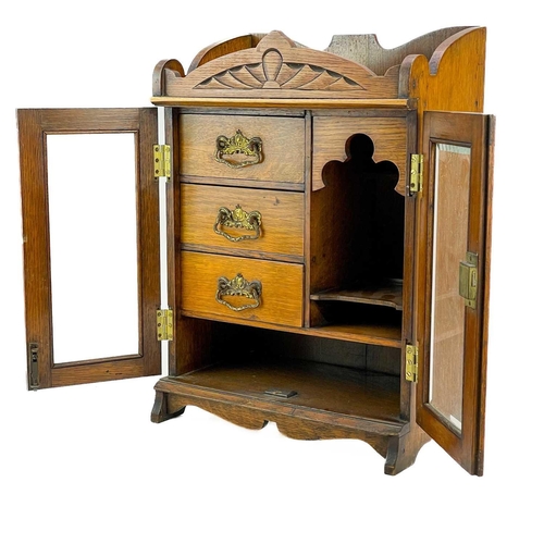 159 - A Late Victorian oak smoker's cabinet. With two glazed doors enclosing drawers and shelves, height 4... 