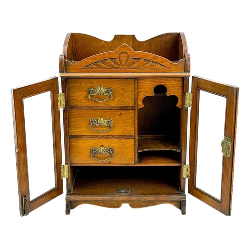 159 - A Late Victorian oak smoker's cabinet. With two glazed doors enclosing drawers and shelves, height 4... 