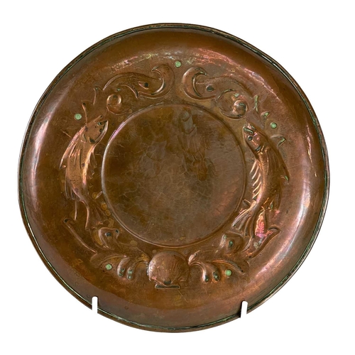 160 - A Newlyn copper circular low dish. The border repousse decorated with two fish, seaweed, and a shell... 