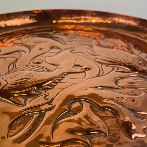 212 - A Newlyn circular copper shallow dish. Repousse and chased decorated with fish amongst seaweed, diam... 