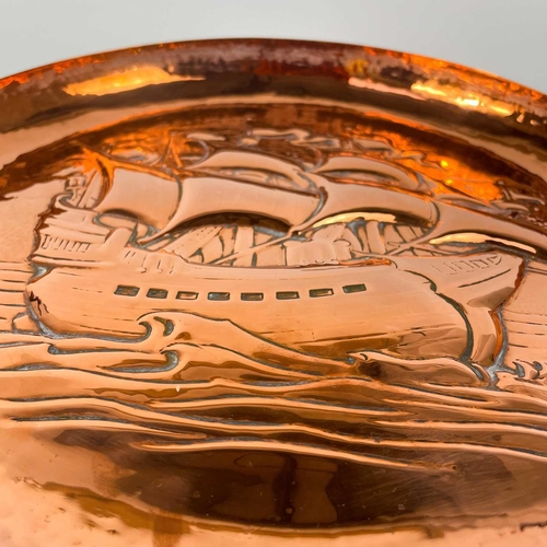 213 - A Newlyn copper circular shallow dish. Repousse and chased decorated with a galleon, diameter 33cm. ... 