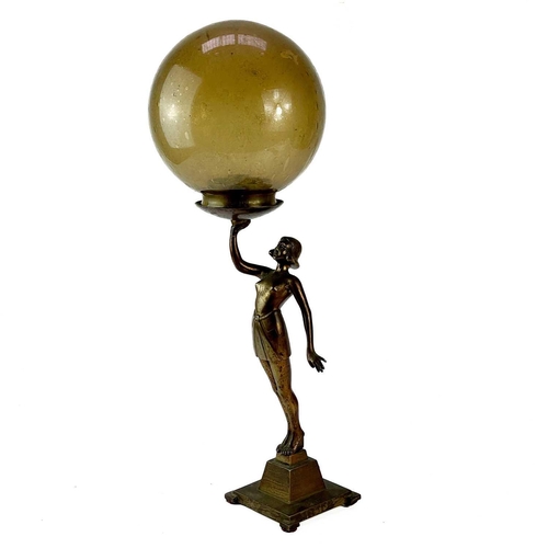 222 - An Art Deco cast metal figural table lamp. Modelled as a standing female dancer holding a large glas... 