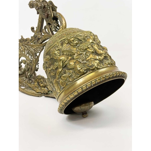 227 - An ornate late Victorian brass bell and wall bracket Cast with cherubs and scrolling foliage, overal... 