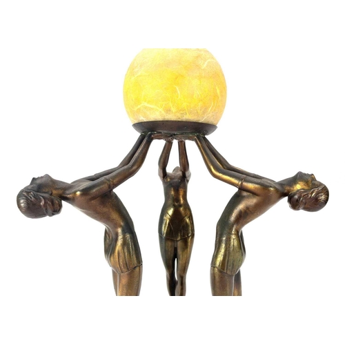 279 - An Art Deco gilt spelter figural table lamp. Modelled with a trio of female dancers lifting a glass ... 