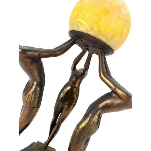 279 - An Art Deco gilt spelter figural table lamp. Modelled with a trio of female dancers lifting a glass ... 