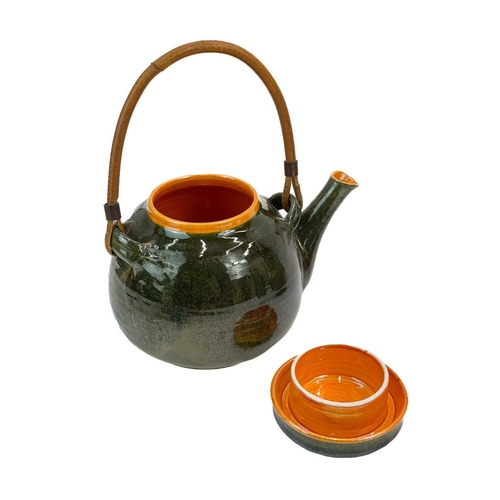 546 - A studio pottery tea pot. In a green glaze with bright orange interior, height including handle 27cm... 