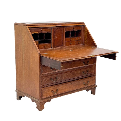 622 - An early 20th century oak bureau. The writing slope opens to reveal an arrangement of drawers and pi... 