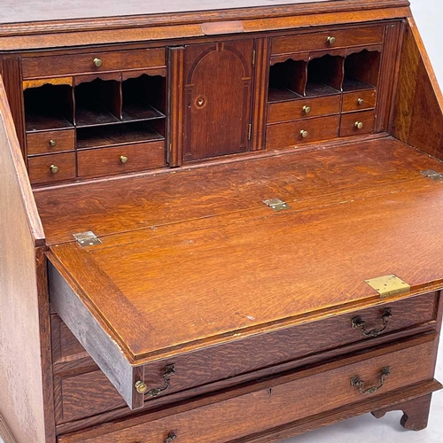 622 - An early 20th century oak bureau. The writing slope opens to reveal an arrangement of drawers and pi... 