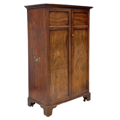 669 - A mahogany two-door wardrobe. 19th century, with a dentil cornice, brass side handles, on bracket fe... 