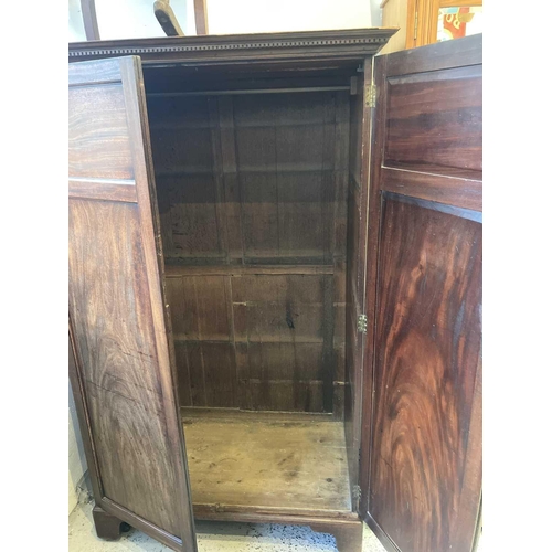 669 - A mahogany two-door wardrobe. 19th century, with a dentil cornice, brass side handles, on bracket fe... 