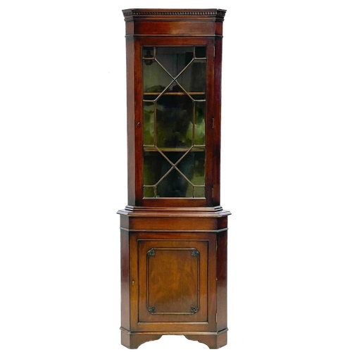 752 - A mahogany standing corner cupboard. 19th century, with a glazed upper part above a panel door with ... 