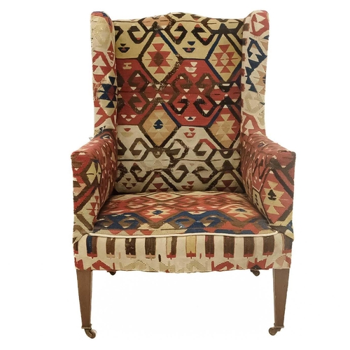 32 - An early 20th century Kelim upholstered wingback armchair. On tapering square supports and ceramic c... 