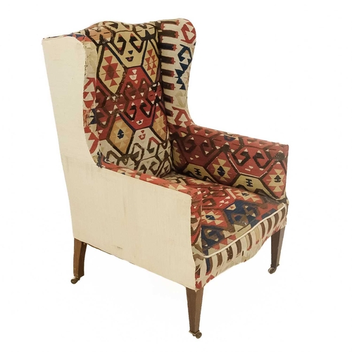 32 - An early 20th century Kelim upholstered wingback armchair. On tapering square supports and ceramic c... 