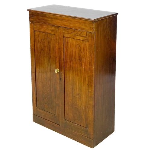 41 - A 19th century mahogany low cupboard. With twin cupboard doors enclosing three half shelves raised o... 