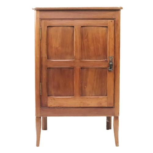 57 - An Arts and Crafts Cotswold school walnut side cupboard. With a single four panelled door, raised on... 