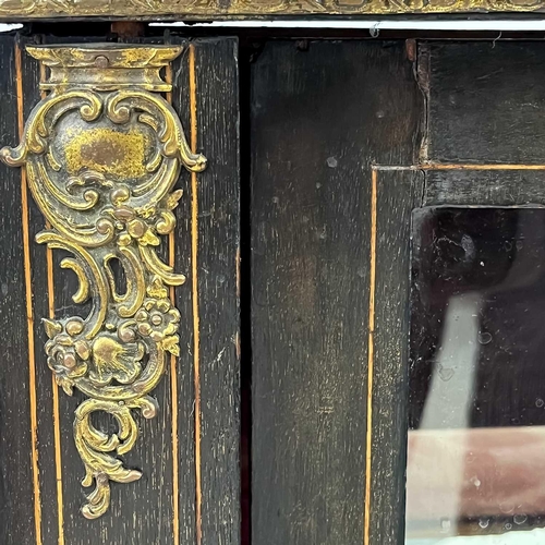 76 - A Victorian ebonised, inlaid and gilt metal mounted display cabinet. The glazed door enclosing two s... 