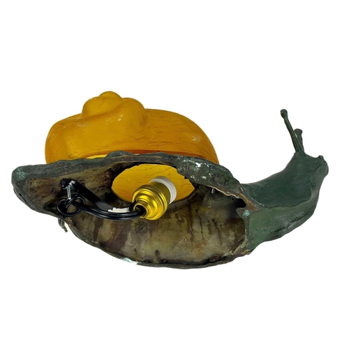 169 - A novelty table lamp in the form of a snail. The simulated bronze body surmounted by an amber glass ... 