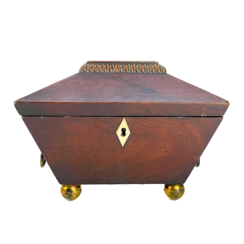 180 - A George III mahogany sarcophagus tea caddy. With twin brass cornicopia handles on brass ball feet. ... 
