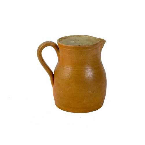 516 - A large pottery jug. Height 32cm together with two other pottery jugs and a large studio pottery dis... 