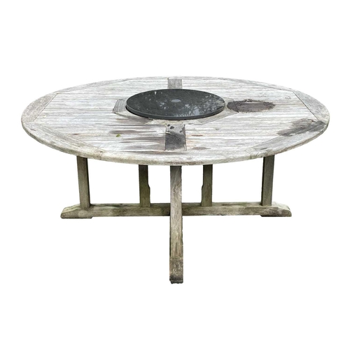 533 - A large circular weathered teak garden table. With polished granite Lazy Susan, diameter of top 180c... 