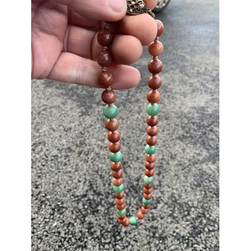 182 - A Chinese green and russet jade bead necklace with silver filigree clasp. The largest bead is 13.5mm... 