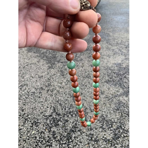 182 - A Chinese green and russet jade bead necklace with silver filigree clasp. The largest bead is 13.5mm... 