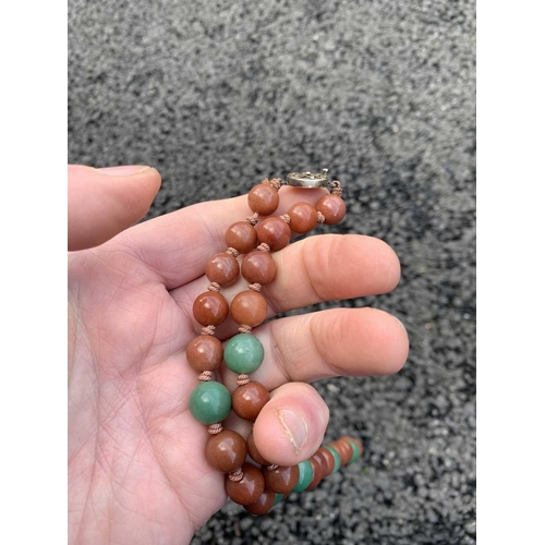 182 - A Chinese green and russet jade bead necklace with silver filigree clasp. The largest bead is 13.5mm... 