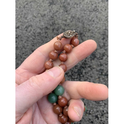 182 - A Chinese green and russet jade bead necklace with silver filigree clasp. The largest bead is 13.5mm... 