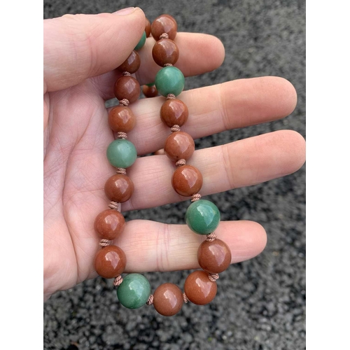 182 - A Chinese green and russet jade bead necklace with silver filigree clasp. The largest bead is 13.5mm... 