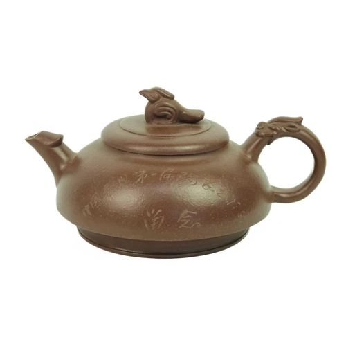 197 - A Chinese Yixing teapot. The cover surmounted by a bird finial above calligraphy opposed by foliage,... 