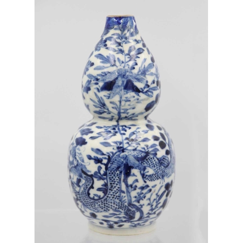 219 - A Chinese blue and white porcelain double gourd vase, circa 1900. Decorated with dragons and floweri... 