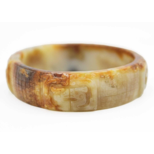 22 - A Chinese carved jade bangle, probably Neolithic period. With russet inclusions, carved with opposin... 