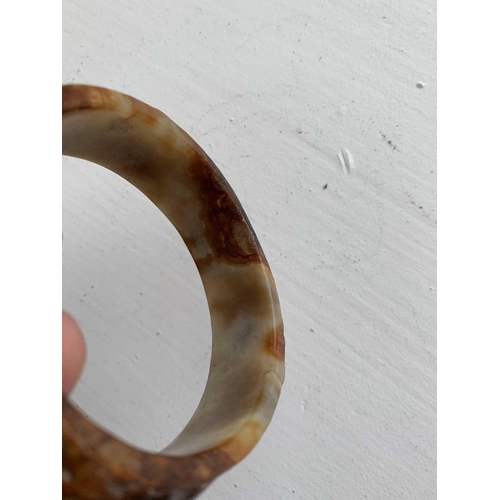 22 - A Chinese carved jade bangle, probably Neolithic period. With russet inclusions, carved with opposin... 