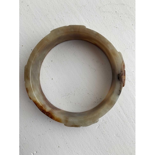 22 - A Chinese carved jade bangle, probably Neolithic period. With russet inclusions, carved with opposin... 